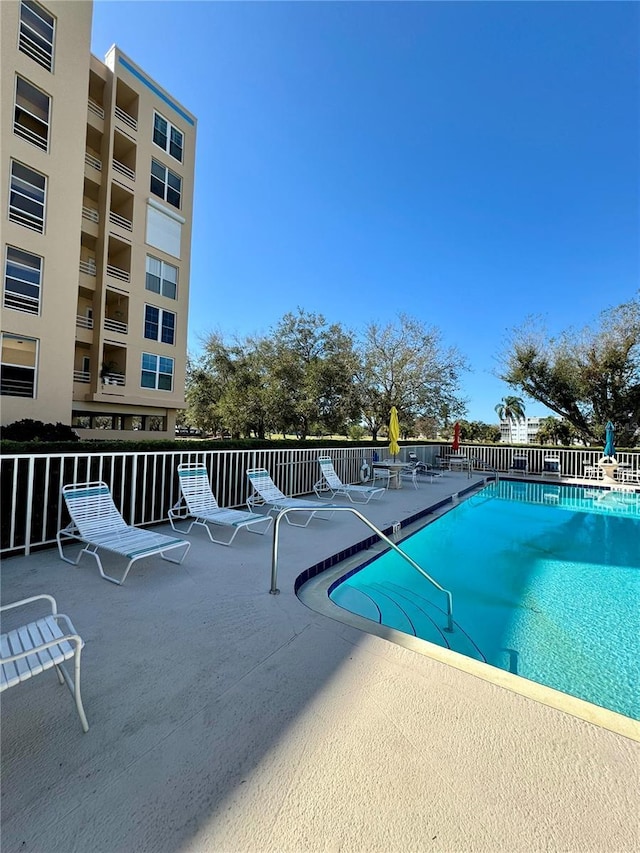 community pool with fence and a patio area