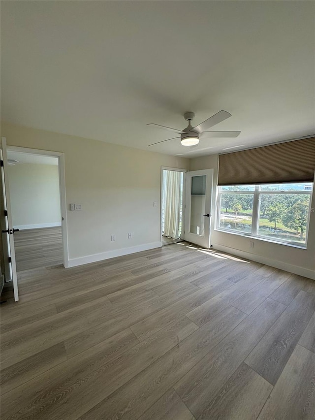 spare room with baseboards, wood finished floors, and a ceiling fan