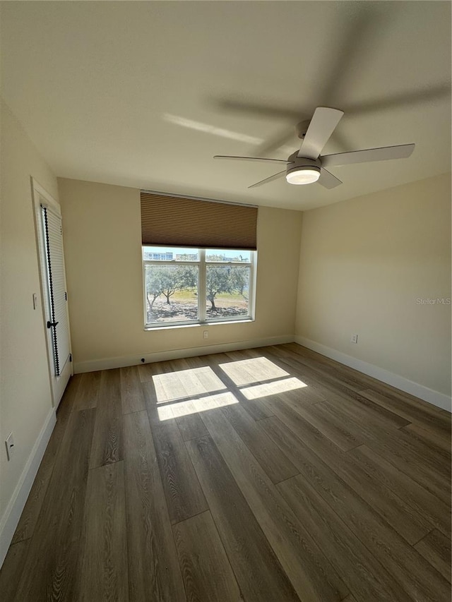 unfurnished room featuring a ceiling fan, dark wood-style flooring, and baseboards