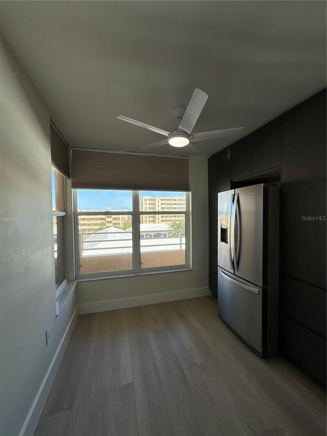 interior space featuring dark cabinetry, a ceiling fan, baseboards, stainless steel fridge with ice dispenser, and light wood-style floors