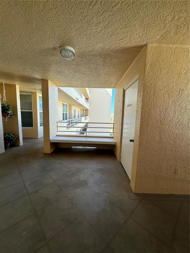 hall with a textured ceiling and a textured wall