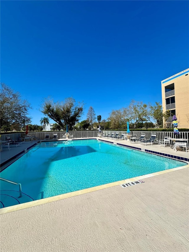 pool with a patio area and fence