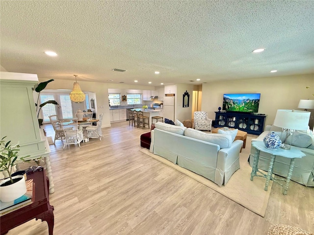 living room featuring visible vents, recessed lighting, a textured ceiling, and light wood-style floors