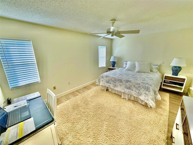 bedroom featuring baseboards, a textured ceiling, wood finished floors, and a ceiling fan