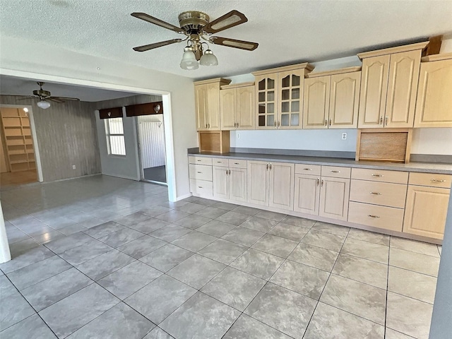 kitchen with light tile patterned floors, a textured ceiling, glass insert cabinets, and ceiling fan