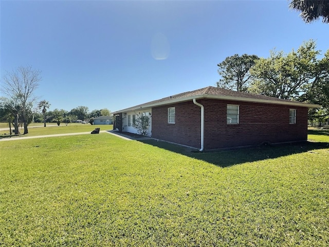 view of side of property with brick siding and a lawn