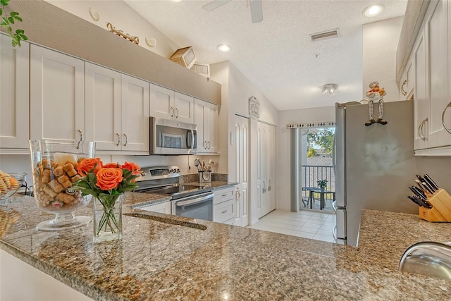 kitchen featuring visible vents, dark stone countertops, a textured ceiling, stainless steel appliances, and white cabinets