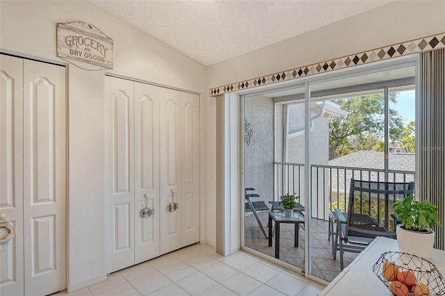 foyer entrance featuring light tile patterned floors, lofted ceiling, and a textured ceiling