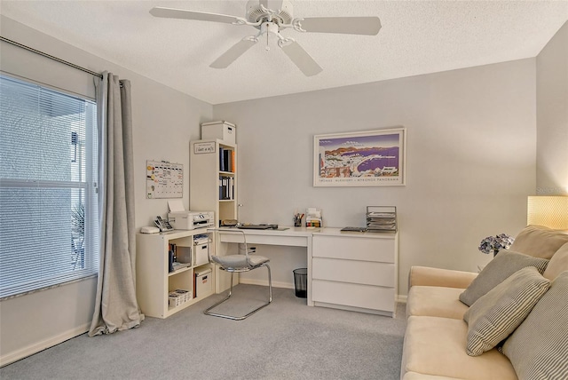 office featuring baseboards, light colored carpet, a ceiling fan, and a textured ceiling