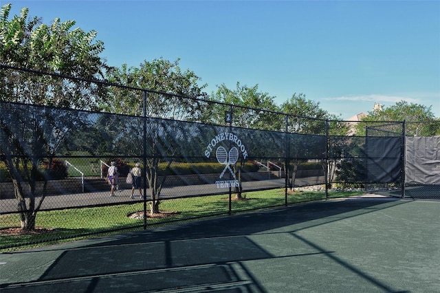 view of tennis court with community basketball court and fence