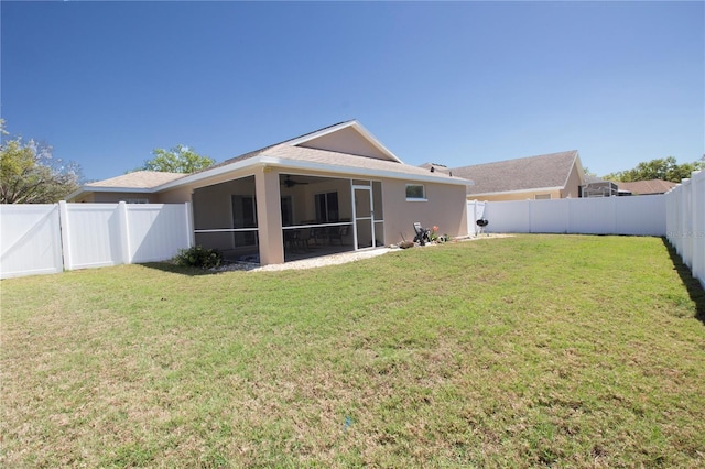 rear view of property featuring stucco siding, a lawn, a fenced backyard, and a sunroom