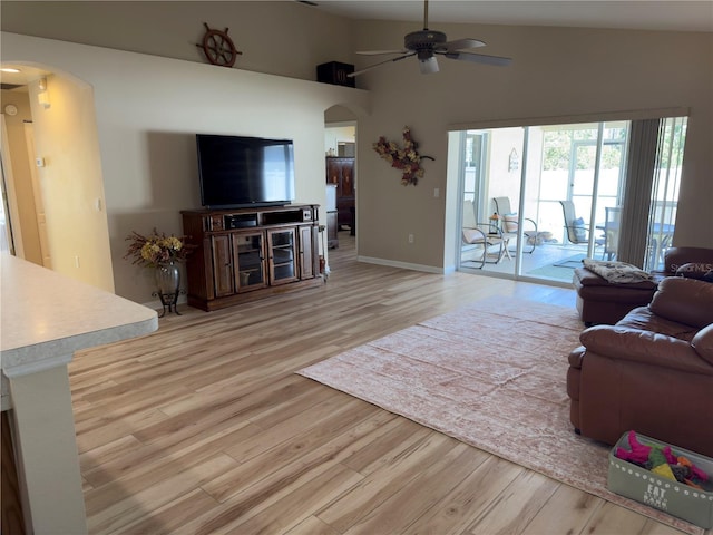 living area with high vaulted ceiling, arched walkways, light wood finished floors, and ceiling fan