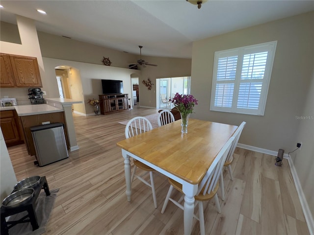 dining space with arched walkways, baseboards, light wood-style floors, and a ceiling fan