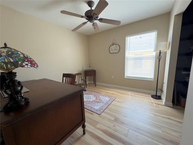 office area featuring light wood finished floors, baseboards, and a ceiling fan