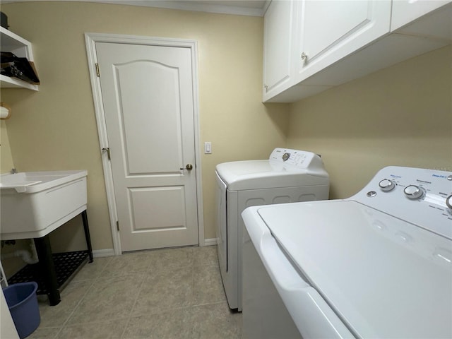 clothes washing area with light tile patterned floors, baseboards, cabinet space, and washing machine and dryer