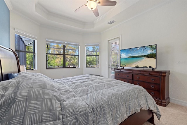 carpeted bedroom featuring a tray ceiling, multiple windows, visible vents, and crown molding