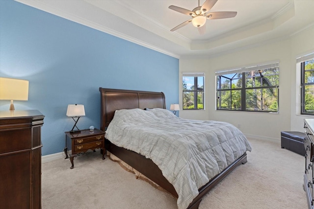 bedroom featuring a ceiling fan, baseboards, a tray ceiling, ornamental molding, and light carpet