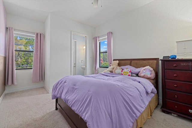 bedroom with ceiling fan, light colored carpet, baseboards, and connected bathroom