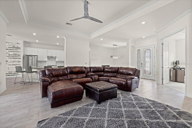 living area featuring visible vents, ornamental molding, a ceiling fan, recessed lighting, and a raised ceiling