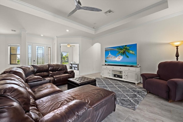 living room featuring visible vents, a raised ceiling, ceiling fan, and ornamental molding
