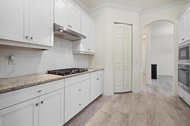 kitchen featuring oven, black gas cooktop, under cabinet range hood, arched walkways, and crown molding