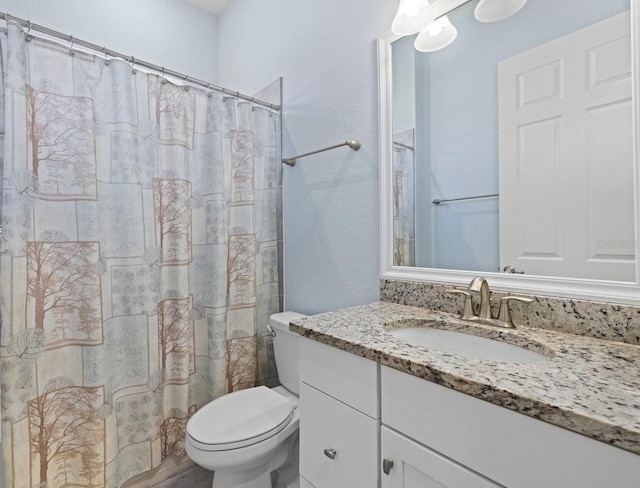 full bath featuring a shower with shower curtain, toilet, and vanity