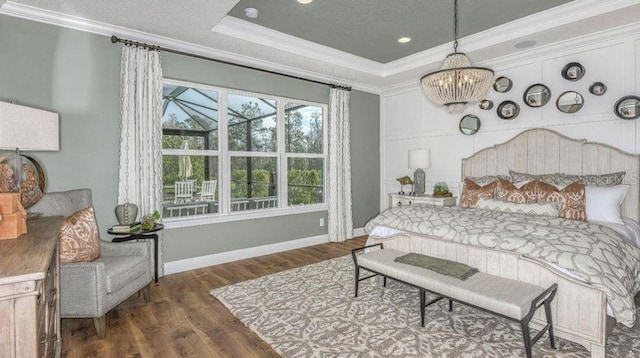 bedroom with a notable chandelier, wood finished floors, a raised ceiling, and ornamental molding