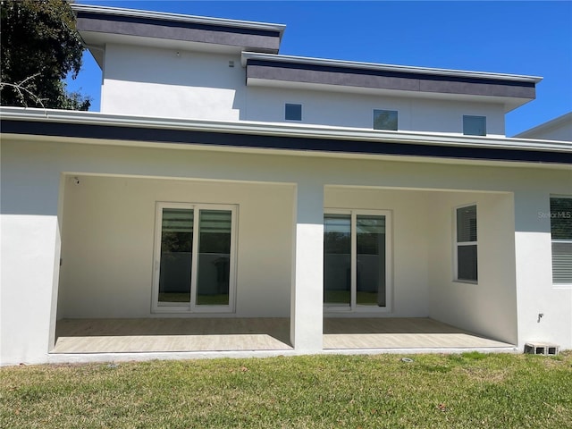 back of house with a patio area, stucco siding, and a yard