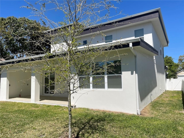 rear view of house featuring a yard, a patio, stucco siding, and fence