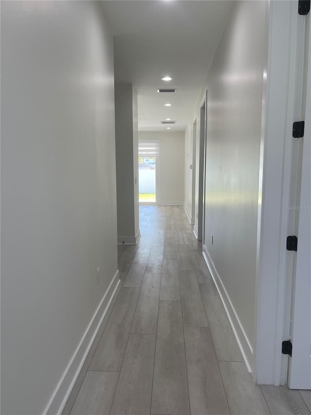 corridor with visible vents, baseboards, and wood finished floors