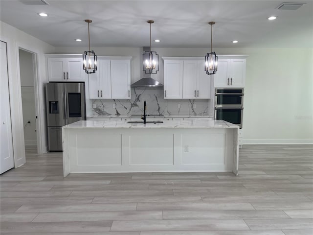 kitchen with visible vents, decorative backsplash, appliances with stainless steel finishes, white cabinetry, and a kitchen island with sink