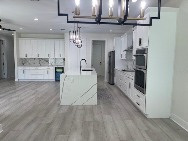 kitchen featuring tasteful backsplash, light stone countertops, light wood-style floors, stainless steel appliances, and a sink