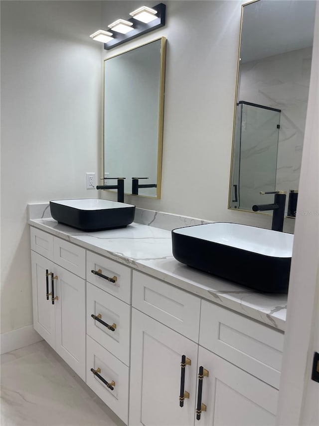 bathroom featuring double vanity, marble finish floor, a marble finish shower, and a sink