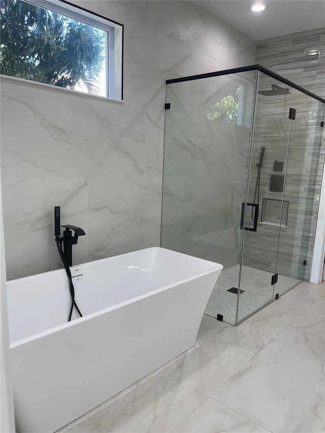 full bathroom featuring recessed lighting, marble finish floor, a stall shower, and a freestanding tub