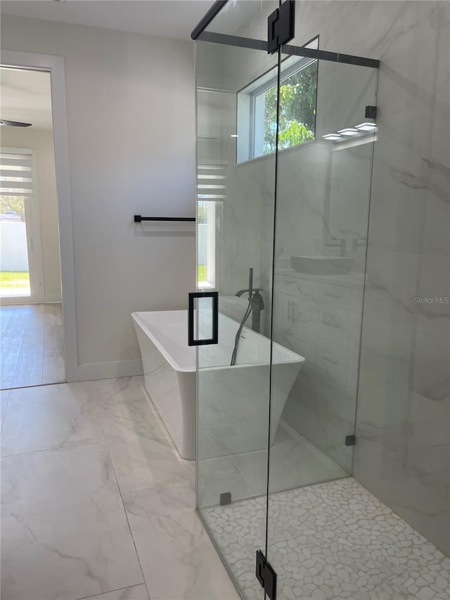 bathroom featuring baseboards, a soaking tub, marble finish floor, and a stall shower