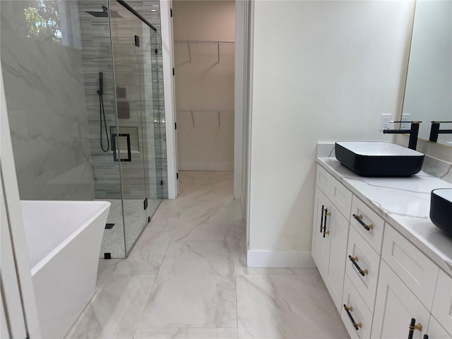 bathroom with double vanity, a sink, a shower stall, a walk in closet, and marble finish floor