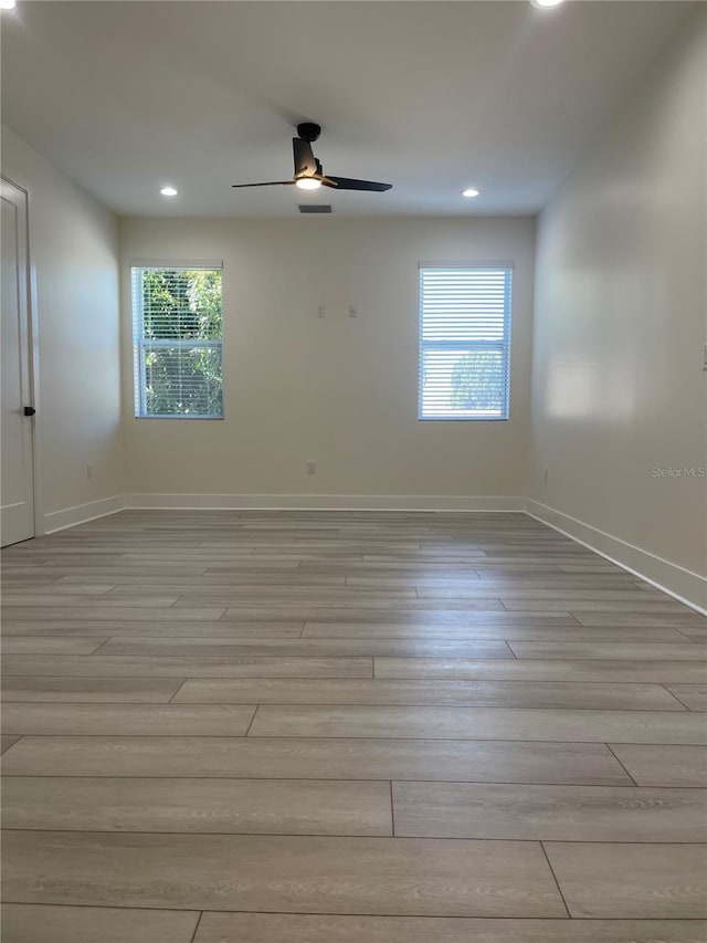 unfurnished room featuring light wood-style flooring, a ceiling fan, and baseboards