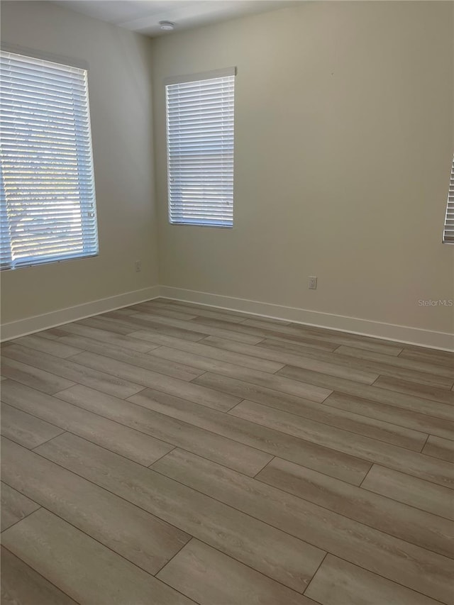 empty room with light wood-style flooring and baseboards