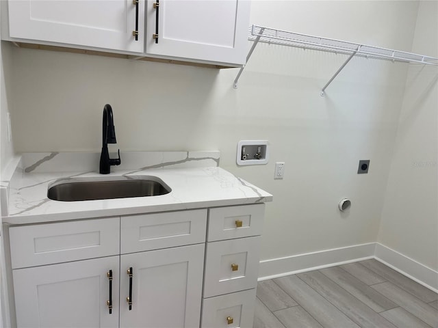 clothes washing area featuring baseboards, hookup for a washing machine, cabinet space, electric dryer hookup, and a sink