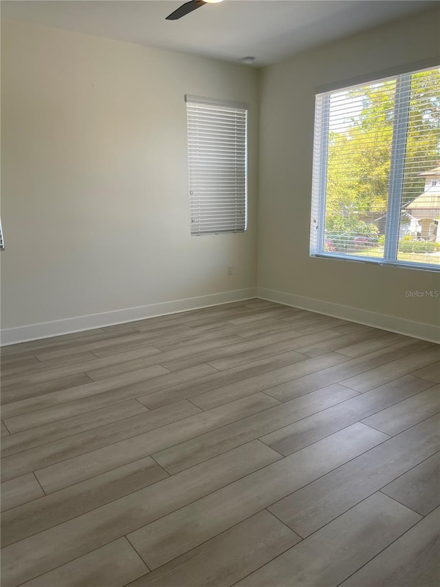 empty room with ceiling fan, baseboards, and wood finished floors