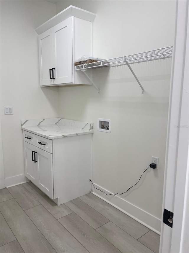 laundry room featuring hookup for a washing machine, cabinet space, baseboards, and wood tiled floor