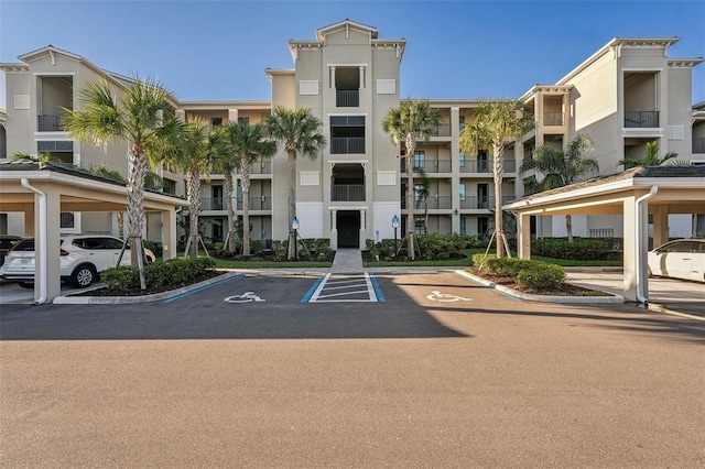 view of building exterior with covered and uncovered parking