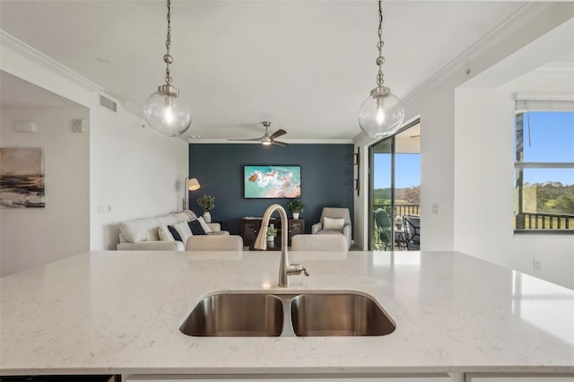 kitchen with crown molding, visible vents, open floor plan, and a sink