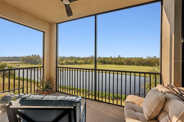 sunroom with ceiling fan and a water view