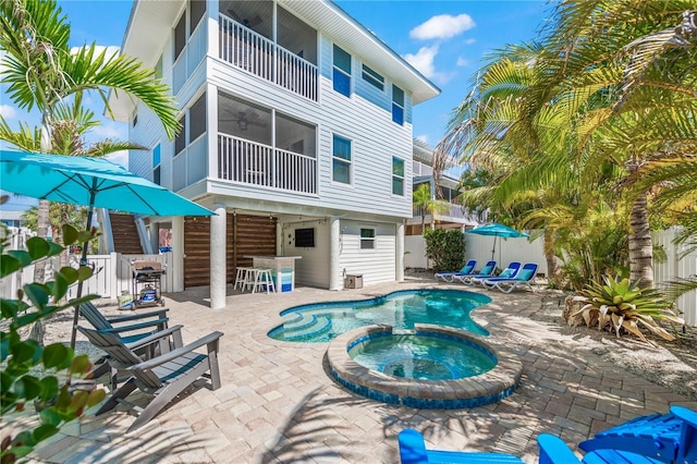 view of swimming pool featuring fence, outdoor dry bar, a patio, and a pool with connected hot tub