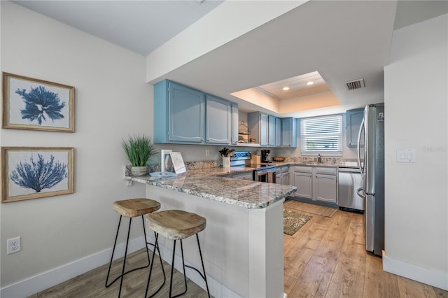 kitchen with a breakfast bar area, appliances with stainless steel finishes, visible vents, baseboards, and a peninsula
