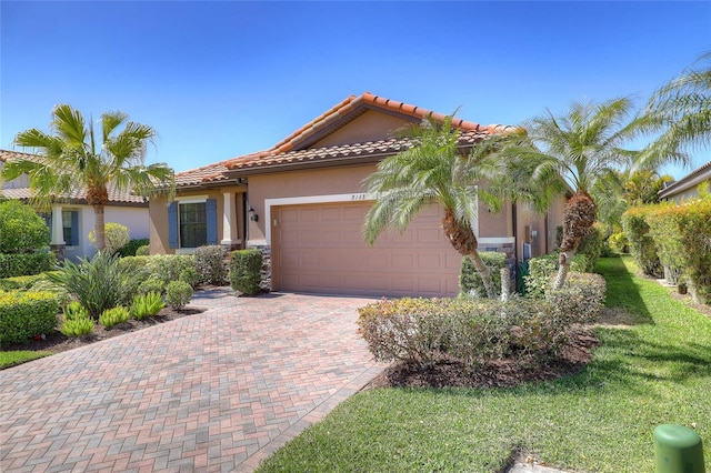 mediterranean / spanish house featuring a garage, decorative driveway, stucco siding, and a tile roof