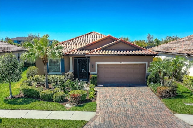 mediterranean / spanish house featuring decorative driveway, an attached garage, stucco siding, and a tile roof