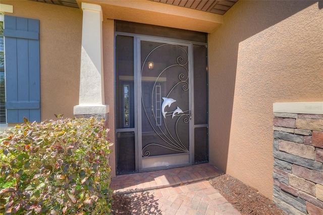 property entrance with stucco siding and stone siding