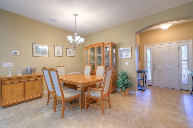 dining space with a notable chandelier, visible vents, arched walkways, and baseboards